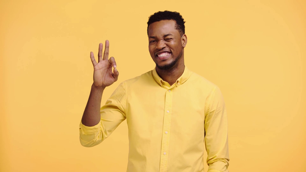 smiling african american man showing okay sign isolated on yellow - Záběry, video