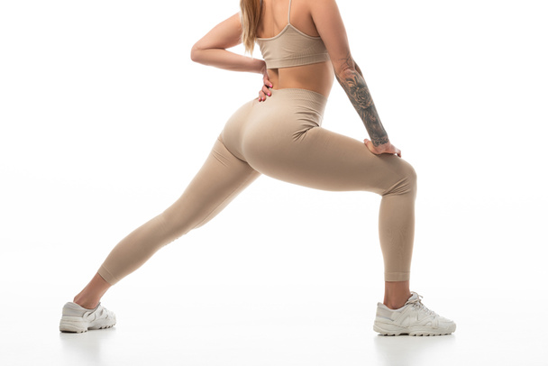 cropped view of tattooed twerk dancer in beige leggings posing isolated on white - Foto, Imagem