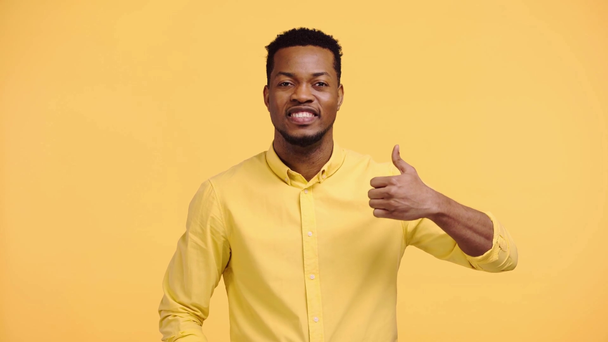 hombre afroamericano feliz mostrando el pulgar hacia arriba aislado en amarillo
 - Metraje, vídeo