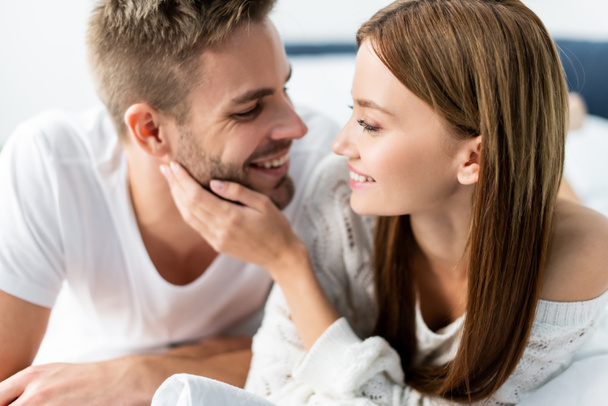 attractive and smiling woman looking at handsome man in apartment  - Photo, Image