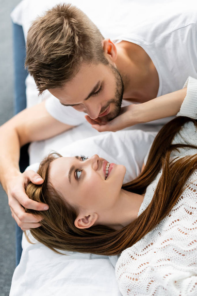 overhead view of handsome man hugging attractive and smiling woman in apartment  - Photo, Image