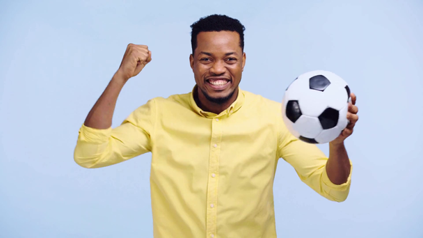 onnellinen afrikkalainen amerikkalainen mies katsomassa jalkapallo peli eristetty sininen
 - Materiaali, video