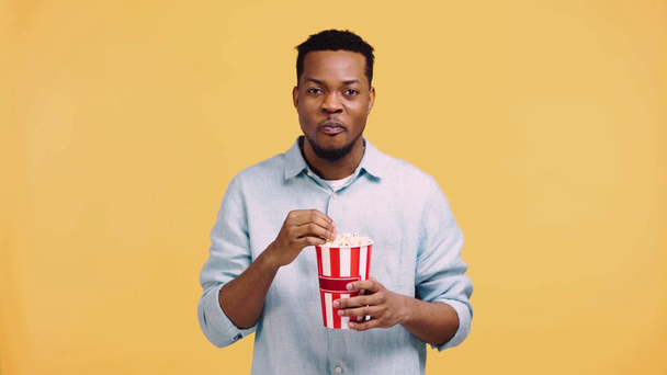 χαμογελαστός Αφροαμερικάνος βλέποντας ταινία απομονωμένη στο κίτρινο - Πλάνα, βίντεο
