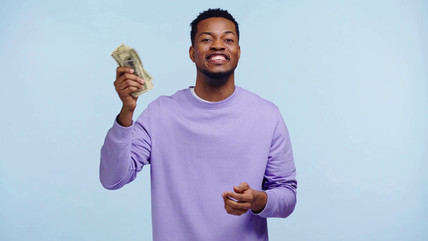 Mutlu Afrikalı Amerikalı adam mavi üzerine izole edilmiş paraları sayıyor. - Video, Çekim