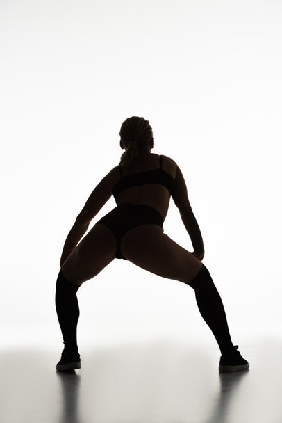zpět pohled na siluetu sexy dívky twerking na podlaze izolované na bílém - Fotografie, Obrázek