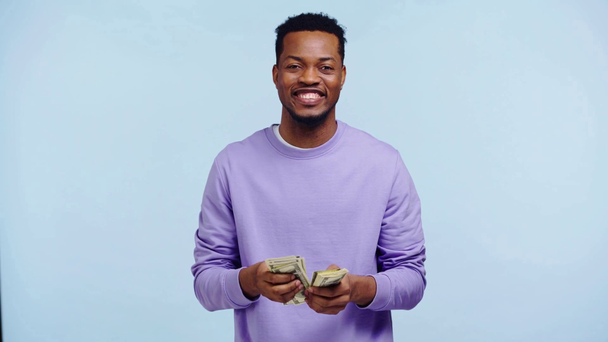 szczęśliwy Afrykanin amerykański człowiek licząc pieniądze odizolowane na niebieski - Materiał filmowy, wideo