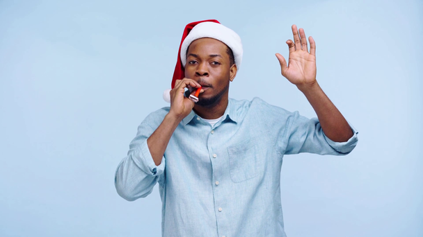 happy african american man blowing in party horn isolated on blue - Filmmaterial, Video