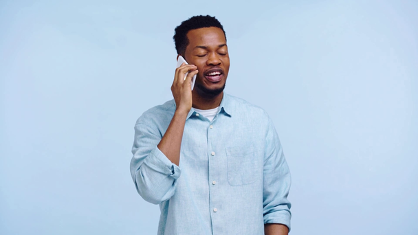 souriant homme afro-américain parler sur smartphone isolé sur bleu
 - Séquence, vidéo