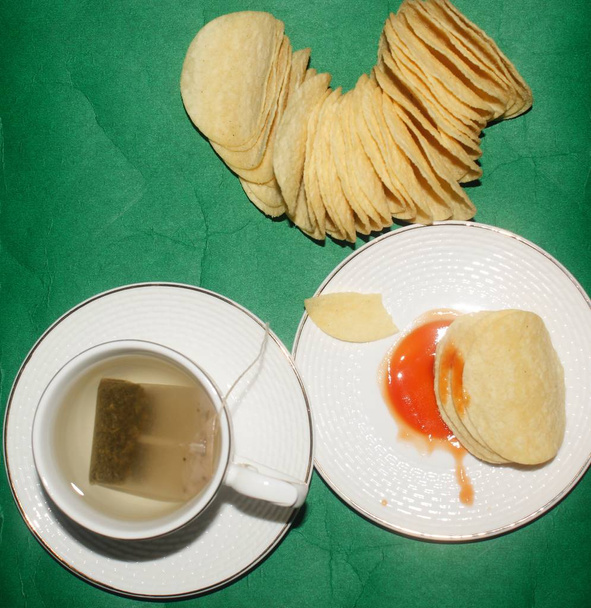 potato wafers served as evening snacks with tea green background - Photo, Image