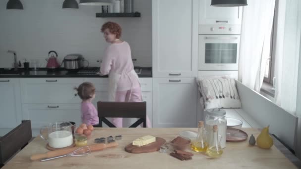 A lányom bejött a konyhába, hogy segítsen anyának főzni. Egy kislány tanul anyától sütit sütni. Anya megtanít egy kislányt édességet készíteni.. - Felvétel, videó