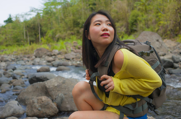 mladá krásná a šťastná asijská Číňanka nesoucí batoh trekking na horách přecházející řeku těší dovolená příroda a svěží prostředí pěší veselá  - Fotografie, Obrázek