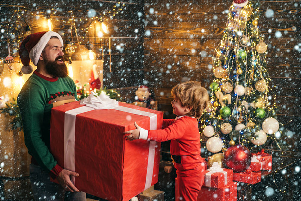 Christmas interior. Happy child with Christmas gift. Cheerful cute child opening a Christmas present. Happy son and father with red Christmas gift box. - Foto, Imagen