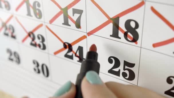 Die weibliche Hand kreuzt mit roter Markierung den Kalendertag 25. Zeitlupenaufnahme. Nahaufnahme - Filmmaterial, Video