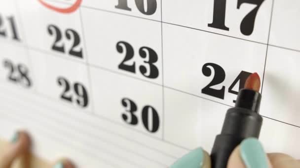 Die weibliche Hand umkreist mit rotem Marker den Kalendertag 24. Zeitlupenaufnahme. Nahaufnahme - Filmmaterial, Video