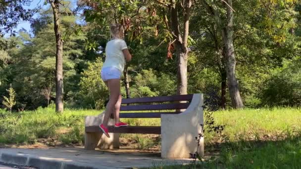 Genç, çekici, zayıf kadın parkta jimnastik yapıyor.. - Video, Çekim