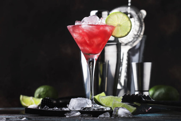 Red Watermelon alcoholic cocktail with vodka, juice, lime and crushed ice, metal bar tools, dark background - Photo, image