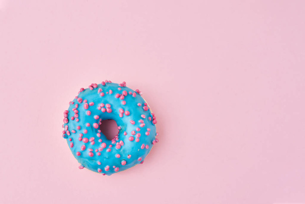 Blue donat decorated sprinkles and icing on a pink background. Creative and minimalis food concept, top view flat lay - Foto, Imagem