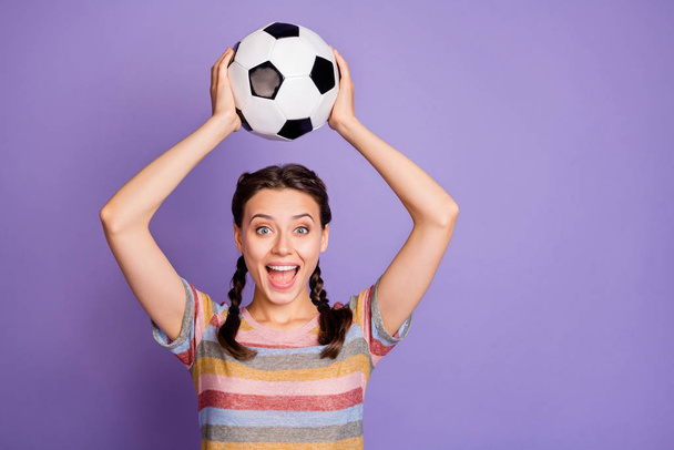 Portrait of excited funky teenager girl hold soccer ball support her team play world cup match win victory scream wow omg wear youth modern clothes isolated over violet color background - Foto, afbeelding