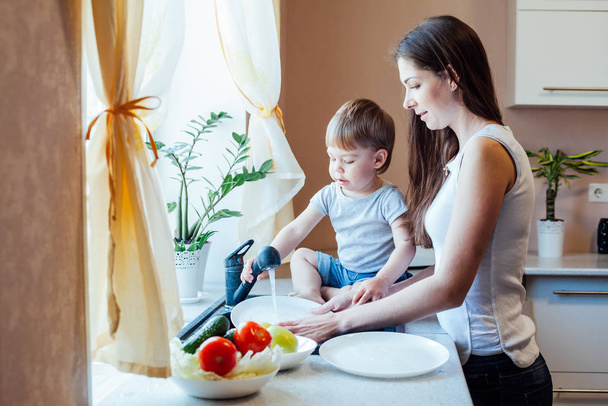 kitchen mom son wash fruits and vegetables - Foto, afbeelding