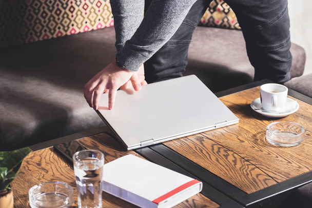 Práce na notebooku, detailní záběr rukou obchodníka v baru s šálkem kávy a diář notebook na stole. Oříznutý obrázek - Fotografie, Obrázek