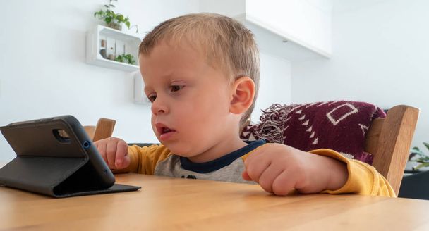 Portrait of toddler boy playing with a smartphone - Fotografie, Obrázek