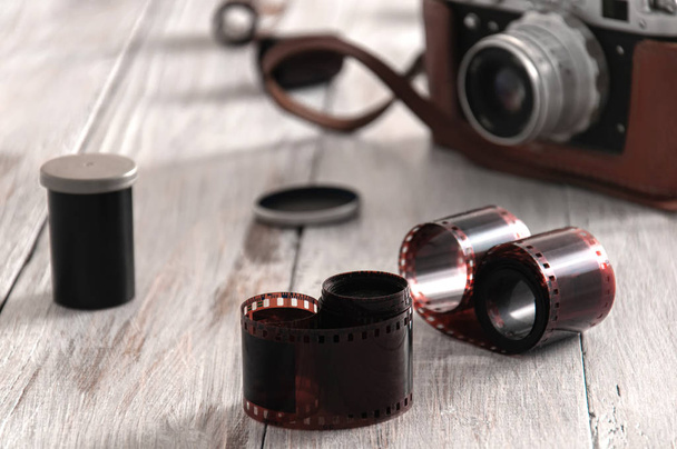 Cámara vieja, bolsa y películas en una mesa de madera gris. Una cámara vintage se apoya sobre una mesa con películas fotográficas
. - Foto, Imagen