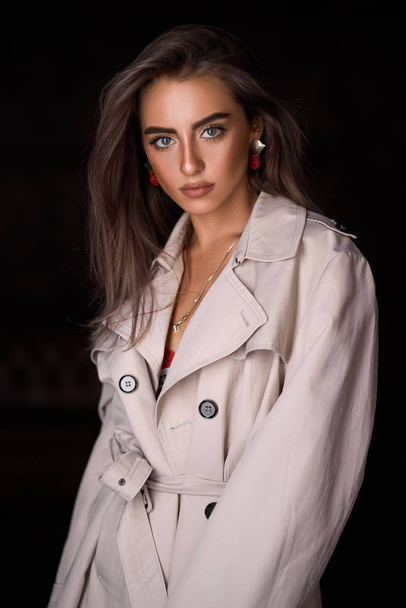 Classic coat on woman on black background. Stylish female portrait with beauty face and trendy hairstyle. - Foto, Imagem