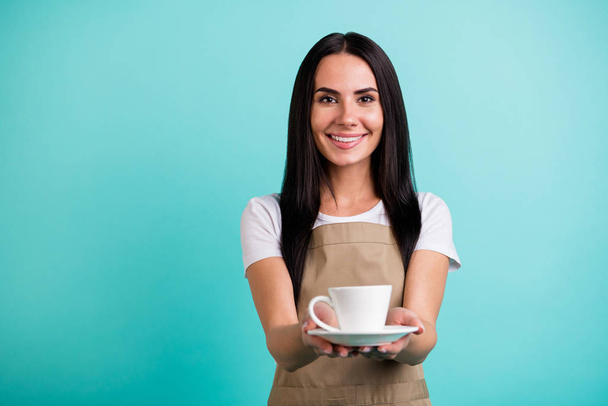 Photo of cheerful cute pretty charming woman server giving you cup of delicious coffee smiling toothily isolated teal color vibrant background - Foto, imagen