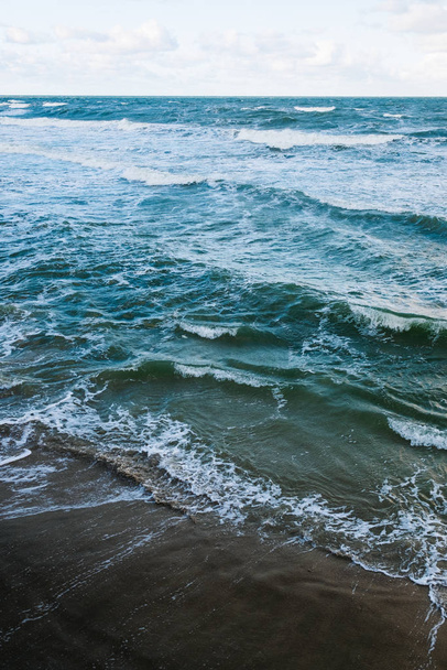 waves on the sandy shore at sunset background. - Φωτογραφία, εικόνα