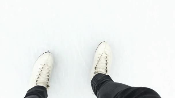 A nők lábai fehér korcsolyában lovagolnak a jégen.. - Felvétel, videó
