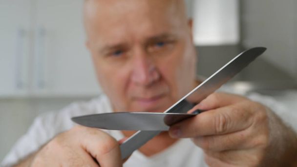 Imagem com o homem afiando uma faca grande usada na cozinha
 - Foto, Imagem