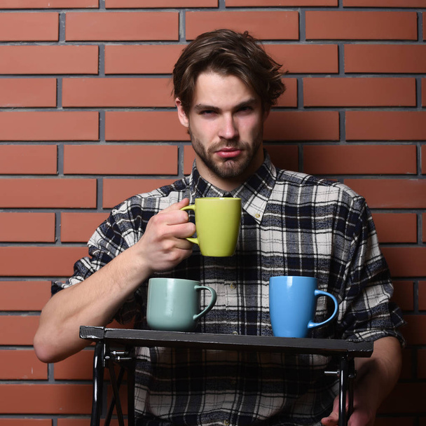 handsome guy holding cups on brick wall background - 写真・画像
