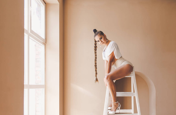 Belle femme danseuse en lingerie sexy posant assise sur l'échelle au studio
 - Photo, image