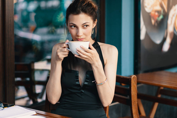 raffinierte Frau genießt Cappuccino oder Latte auf einem lebendigen, farbenfrohen Hintergrund drinnen. - Foto, Bild