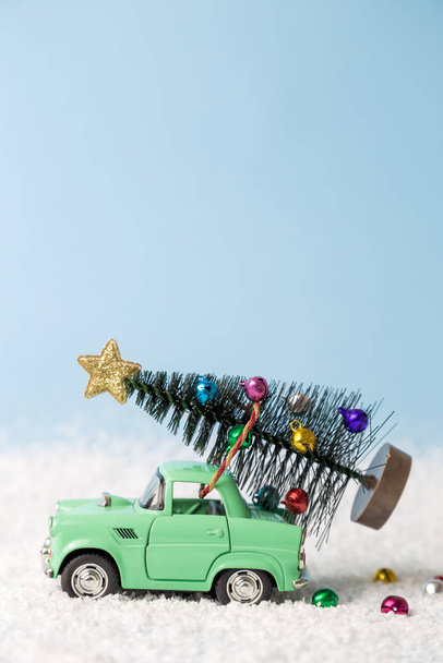 Jouet voiture rétro avec arbre de Noël conduisant vers le haut de la montagne enneigée concept de vacances d'hiver créatif minimum
. - Photo, image