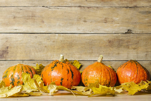 Zucche e foglie autunnali su uno sfondo di legno. Concetto di Halloween, raccolto, vigilia di Halloween - Foto, immagini