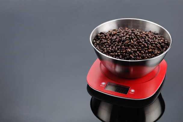 Coffee beans in bowl on an electronic scale on grey mirror backg - Photo, Image