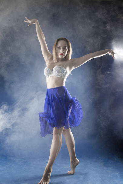 girl dancer in a jump and a beautiful pose on a blue background - Photo, image