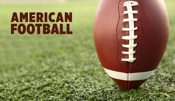 Регбійний м'яч і текст AMERICAN FOOTBALL на зеленій траві
 - Фото, зображення