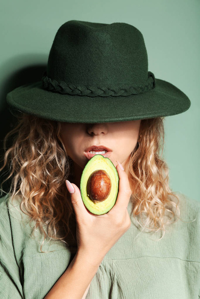 Fashionable young woman with avocado on color background - Photo, Image