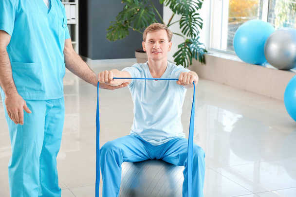 Физиотерапевт, работающий с пациентом-мужчиной в реабилитационном центре
 - Фото, изображение