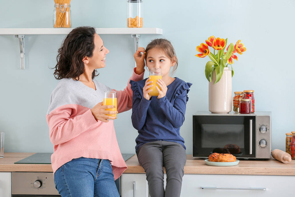 Petite fille avec sa mère buvant du jus dans la cuisine
 - Photo, image