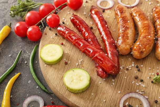 Salsichas grelhadas saborosas com legumes e especiarias em tábua de madeira
 - Foto, Imagem