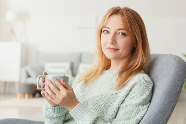 Beautiful mature woman drinking coffee at home - Фото, изображение