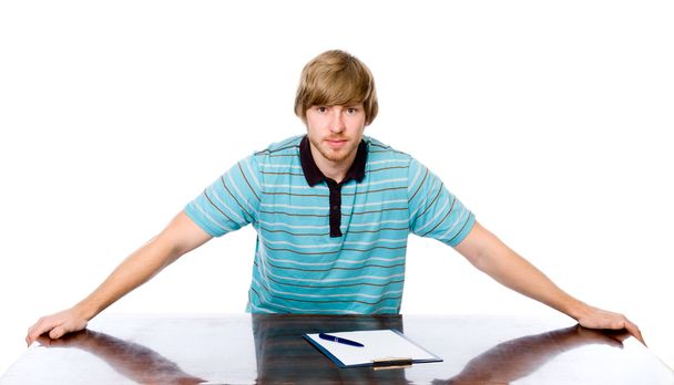 Portret van een jonge man zit achter een bureau. - Foto, afbeelding