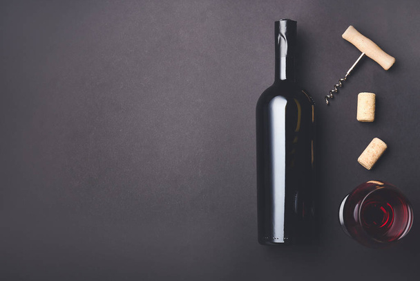 Bottle and glass of wine with corks and opener on dark background - Valokuva, kuva