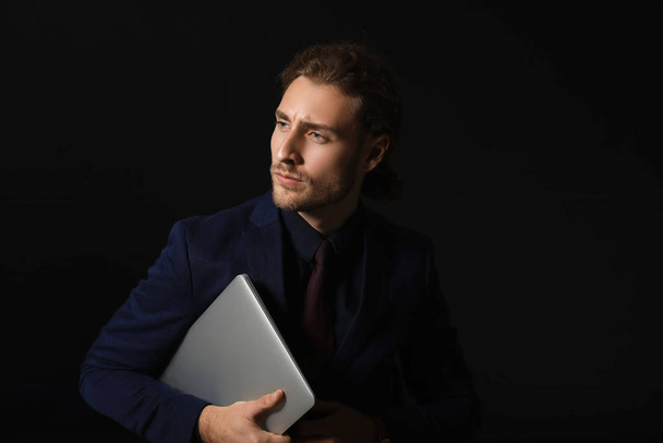 Portrait of handsome businessman with tablet computer on dark background - Foto, imagen