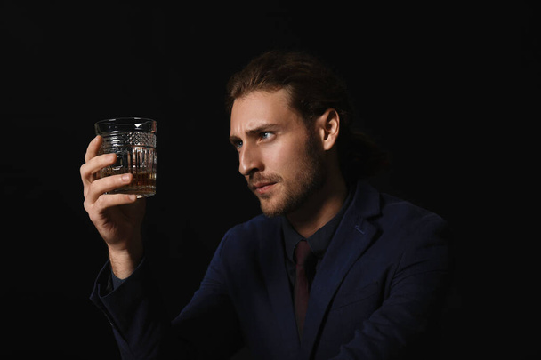 Πορτρέτο του όμορφου επιχειρηματία με ένα ποτήρι αλκοόλ σε σκούρο φόντο - Φωτογραφία, εικόνα