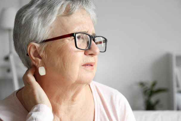 Donna anziana che soffre di dolore al collo a casa
 - Foto, immagini