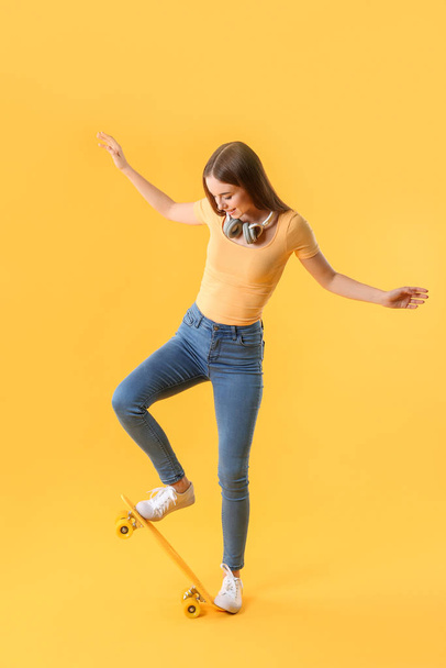 Stylish hipster girl with skateboard on color background - Foto, afbeelding